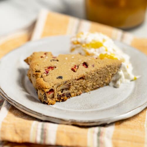 A vegan gluten-free rhubarb date scone on a plate with citrus ginger nondairy whipped cream.